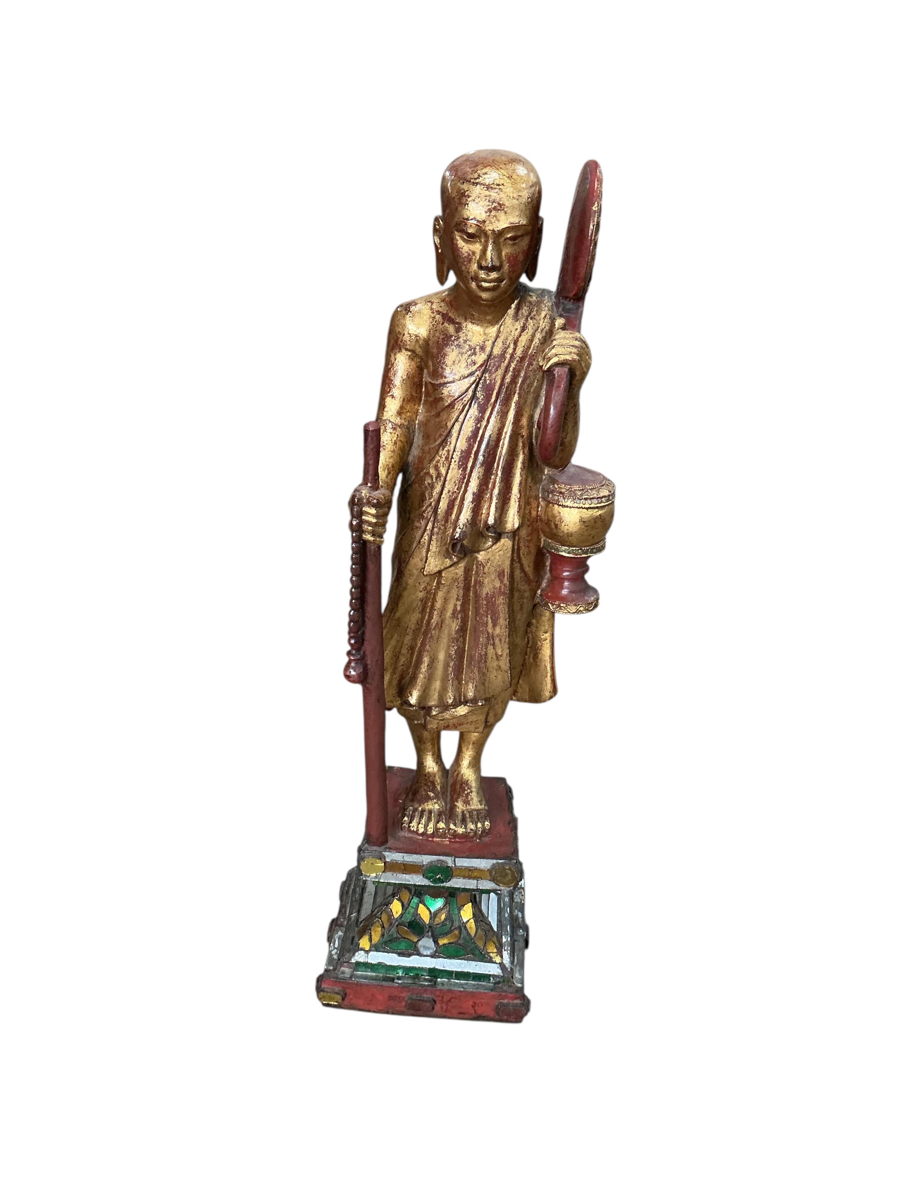 A Tibetan or Thai carved giltwood figure of a priest on a mirrored plinth, height 80cm